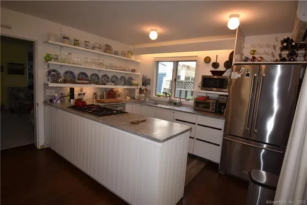 a kitchen with stainless steel appliances granite countertop a refrigerator a sink a stove and a refrigerator