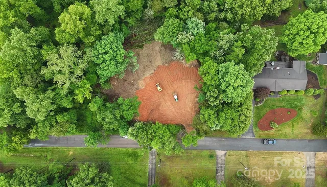 an aerial view of residential house with outdoor space and trees all around
