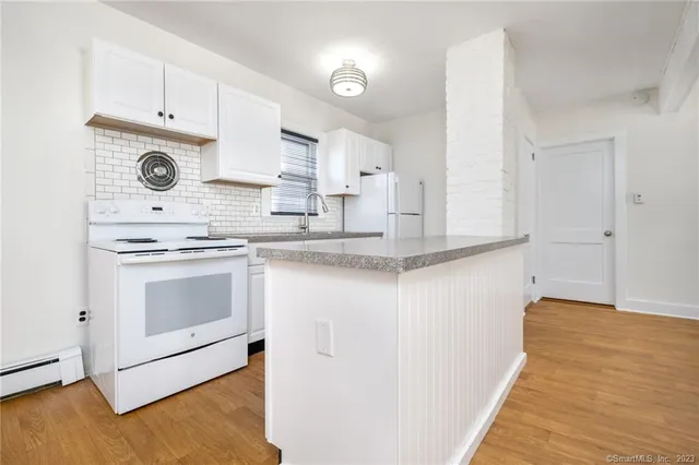 a kitchen with granite countertop white cabinets and white appliances
