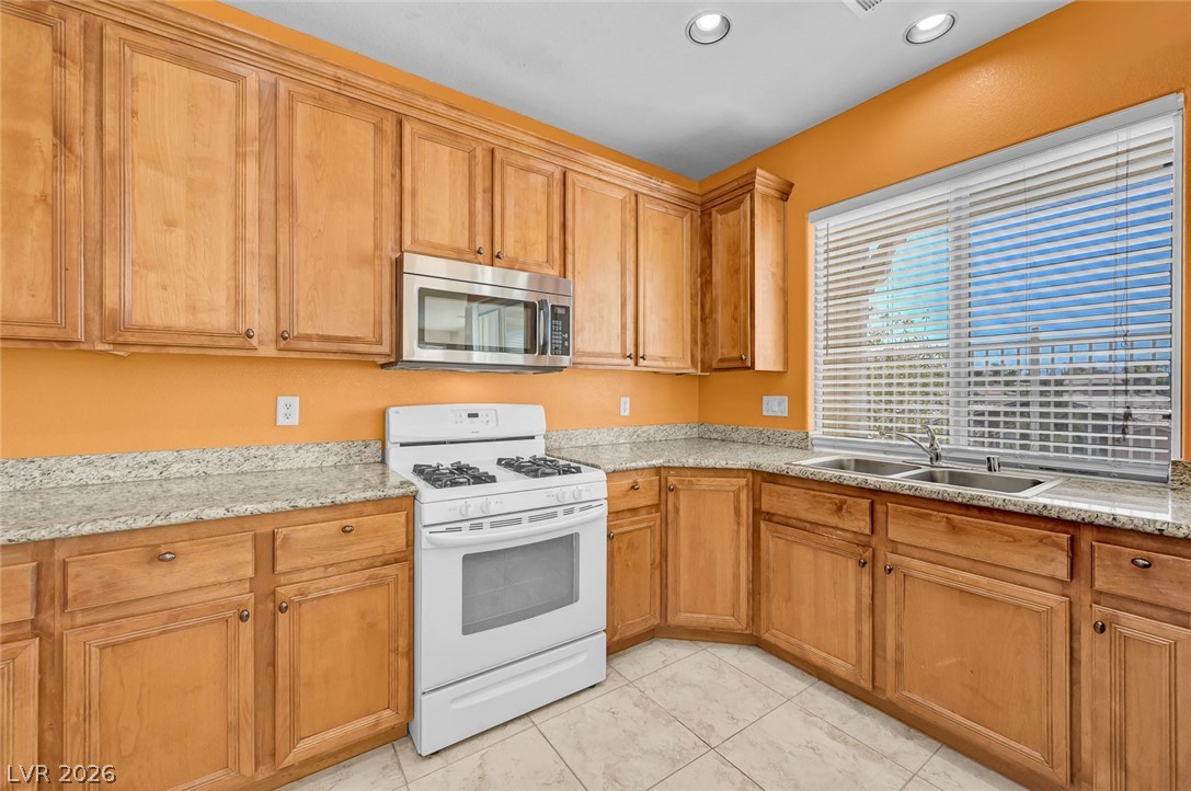977 Sparkling Light Street Henderson, NV 89052 - Photo 30 of 75 This bright kitchen features ample wood cabinetry, granite countertops, and a functional layout.