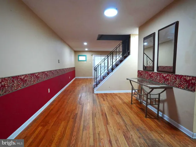 a hallway with wooden floor pool table and stairs