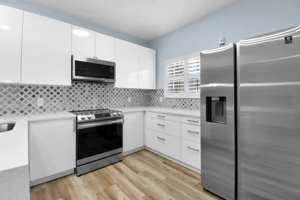 a kitchen with stainless steel appliances white cabinets a stove a sink and a refrigerator