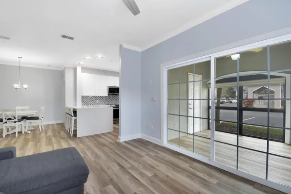 a large white kitchen with wooden floor and a large window