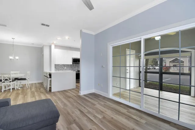 a large white kitchen with wooden floor and a large window