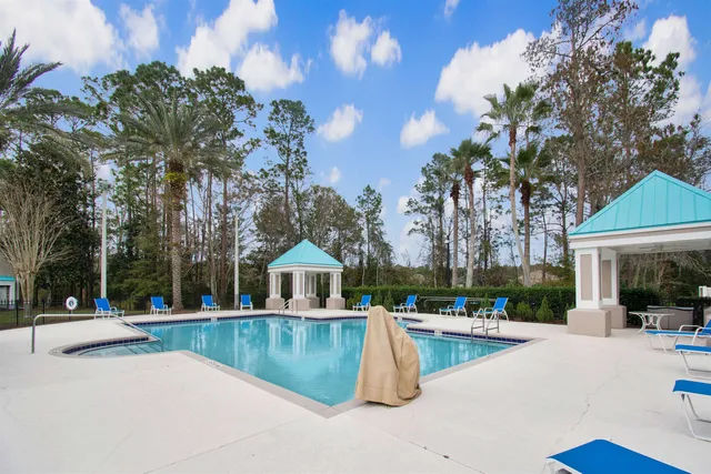 a view of swimming pool with outdoor seating and house in the background