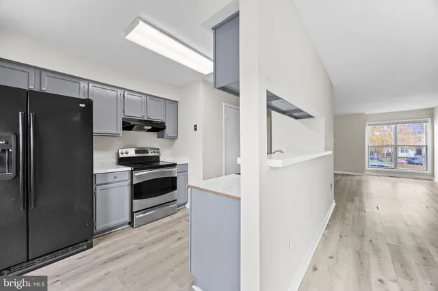 a kitchen with a refrigerator a stove top oven and cabinets