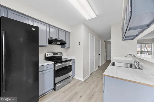 a kitchen with granite countertop a refrigerator stove and sink