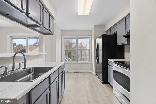a kitchen with granite countertop a stove a sink and a refrigerator