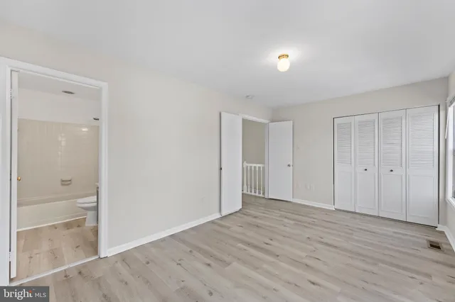 a view of an empty room with wooden floor and closet