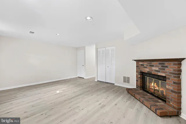 an empty room with wooden floor fireplace and a window