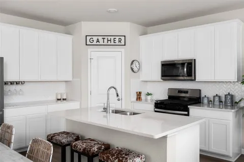 a kitchen with stainless steel appliances a sink a stove a microwave a refrigerator and cabinets