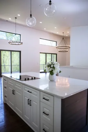 a kitchen with kitchen island granite countertop a sink and white cabinets with wooden floor