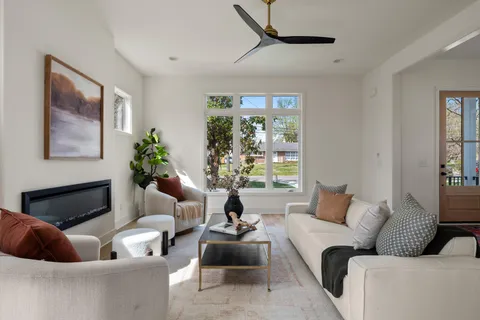 a living room with furniture a chandelier and a large window