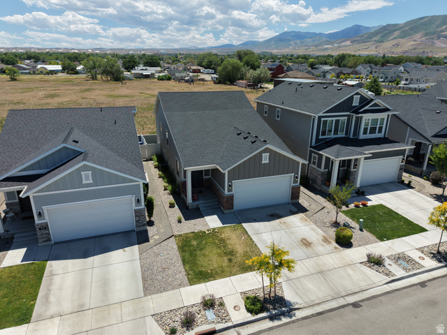 7687 West Mount Elinor Road Magna, UT 84044 - Photo 43 of 43 Contemporary residential exterior with an attached two-car garage, dark asphalt shingle roof, light gray siding, and stone accents