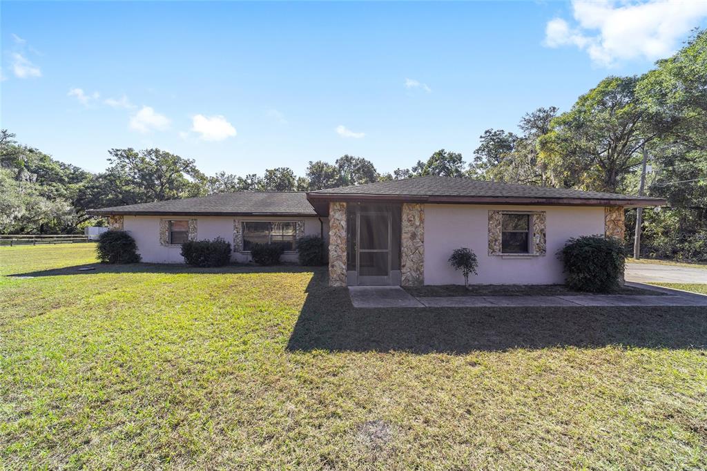 10700 Southeast Sunset Harbor Road Summerfield, FL 34491 - Photo 7 of 41 a front view of a house with a yard and garage