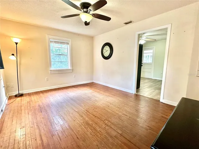 a view of an empty room with wooden floor and a window