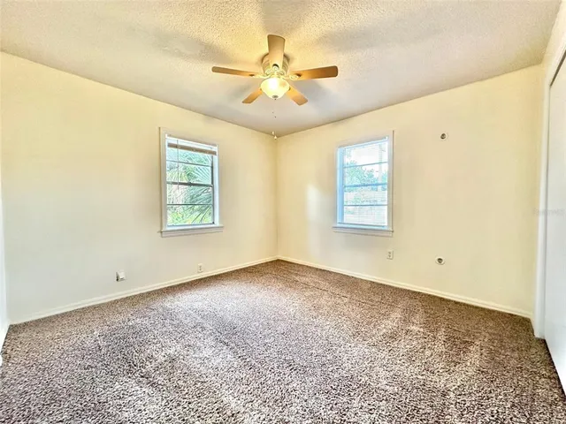 an empty room with windows and ceiling fan