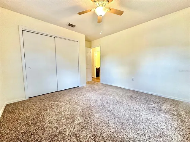 an empty room with a ceiling fan and carpet