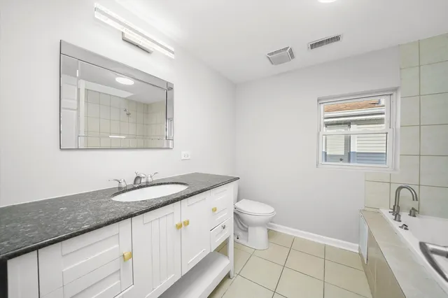 a kitchen with stainless steel appliances granite countertop a stove top oven a sink a refrigerator and white cabinets with wooden floor