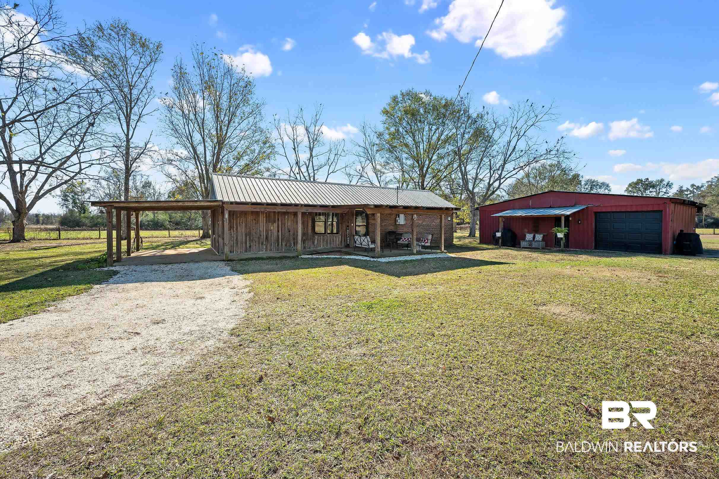110 Sam Jones Road Atmore, AL 36502 - Photo 8 of 47 Back of property featuring a lawn, an outdoor structure, covered porch, driveway, and a metal roof