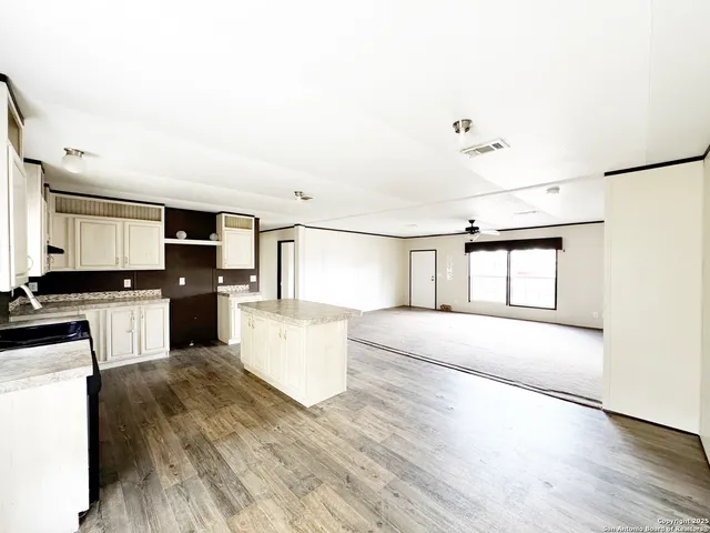 a large white kitchen with sink a microwave and cabinets