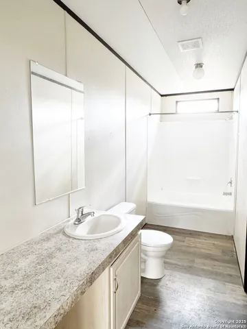 a bathroom with a granite countertop sink a toilet and shower