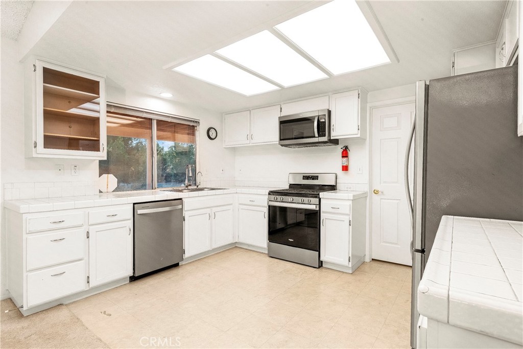 9642 East Ave R 14 Littlerock, CA 93543 - Photo 56 of 66 a kitchen with white cabinets and stainless steel appliances