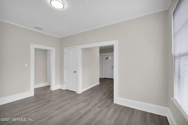 an empty room with wooden floor and windows