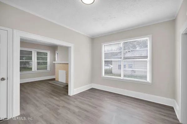 an empty room with wooden floor and windows