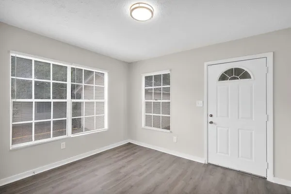 an empty room with wooden floor and windows