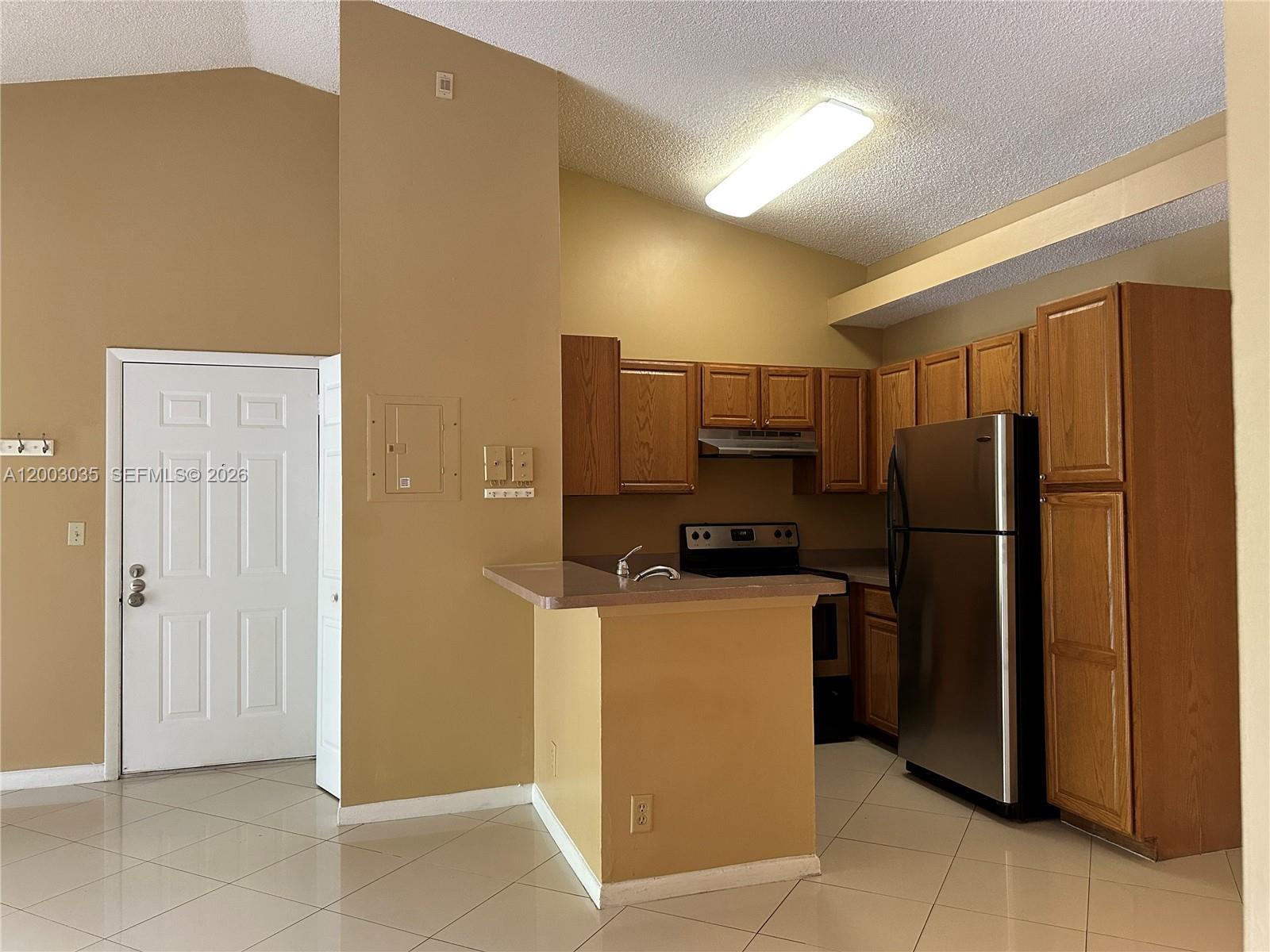 731 Lyons Road, Unit 16203 Coconut Creek, FL 33063 - Photo 3 of 14 a kitchen with a refrigerator a stove top oven and cabinets