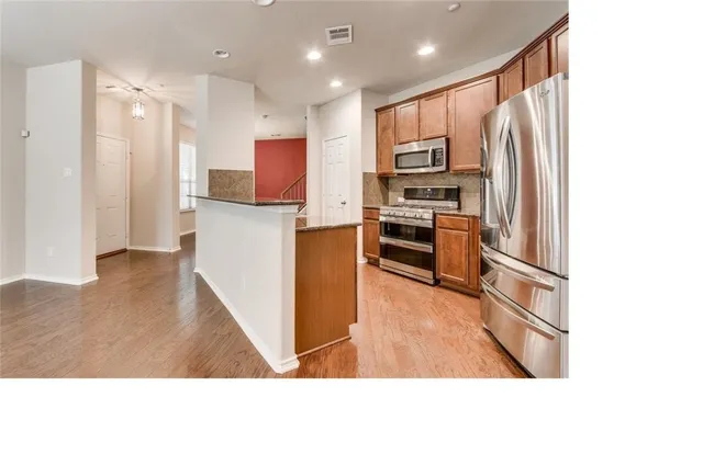 a kitchen with stainless steel appliances kitchen island granite countertop a refrigerator and a stove