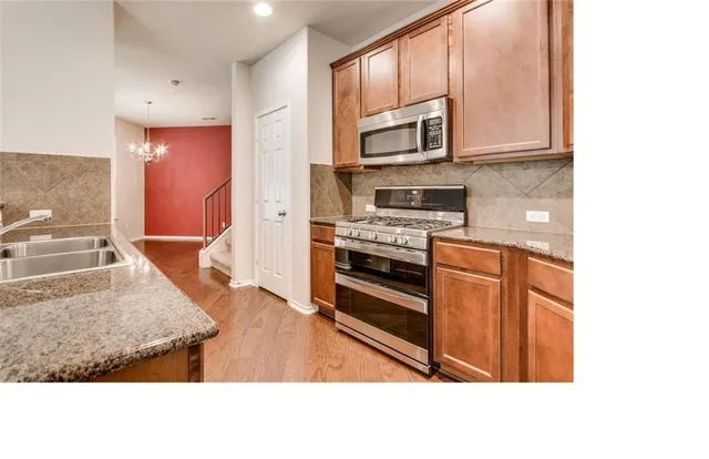 a kitchen with stainless steel appliances granite countertop a stove a sink and a microwave