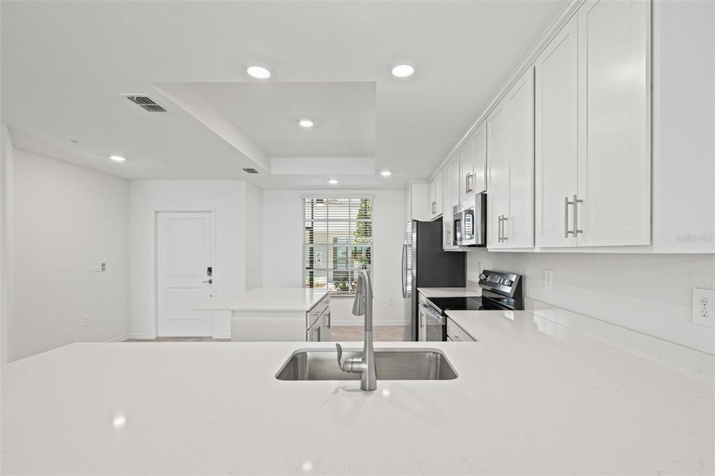 19007 Scallop Loop, Unit 108 Lakewood Ranch, FL 34211 - Photo 16 of 59 a large white kitchen with sink and a large mirror