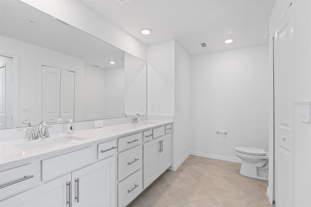 19007 Scallop Loop, Unit 108 Lakewood Ranch, FL 34211 - Photo 23 of 59 a spacious bathroom with a double vanity sink a toilet and a mirror