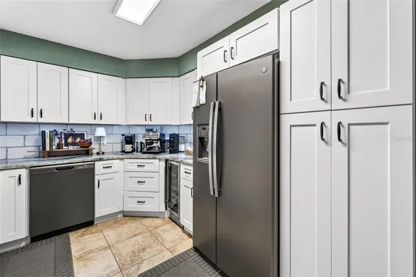 a kitchen with stainless steel appliances granite countertop a refrigerator sink and white cabinets