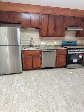 a kitchen with granite countertop a refrigerator sink and cabinets