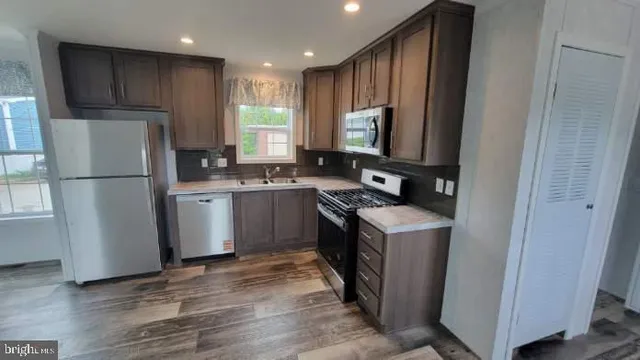 a kitchen with a refrigerator a stove a sink dishwasher and wooden cabinets with wooden floor