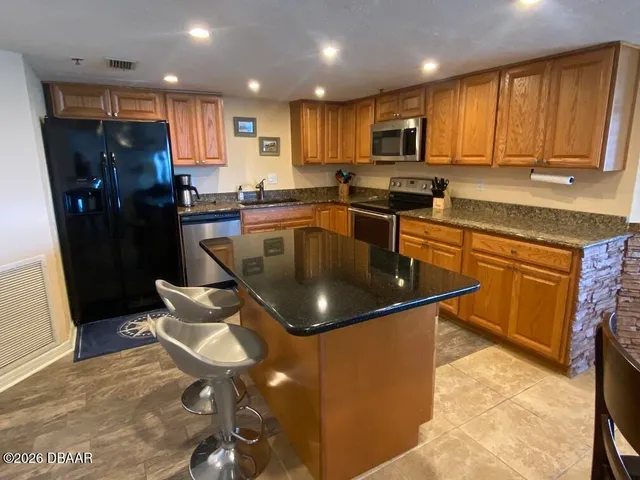 a kitchen with stainless steel appliances granite countertop a sink stove refrigerator and cabinets
