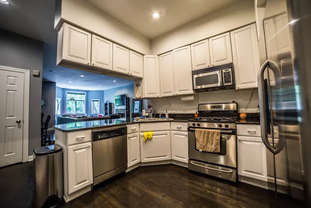a kitchen with stainless steel appliances granite countertop a refrigerator a stove top oven a sink and cabinets