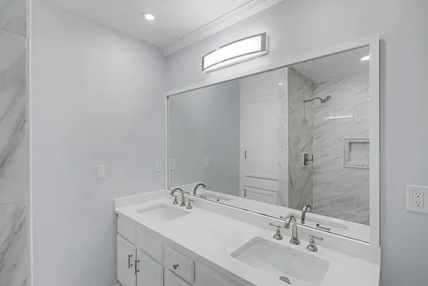 a bedroom with a bed a mirror on dresser and a chandelier