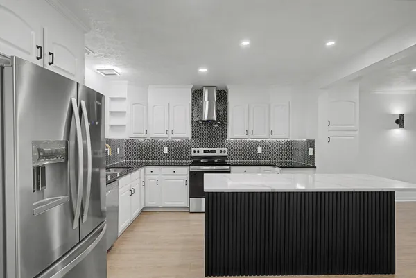 a kitchen with stainless steel appliances granite countertop a refrigerator a sink a stove and oven