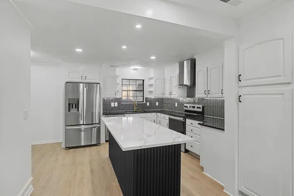 a kitchen with kitchen island a counter top space stainless steel appliances and cabinets