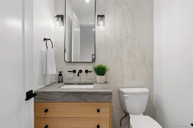 a bathroom with a granite countertop toilet sink and mirror