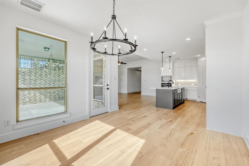 147 Derrett Lane Rhome, TX 76078 - Photo 27 of 28 Kitchen featuring open floor plan, an island with sink, light wood finished floors, a chandelier, and decorative backsplash