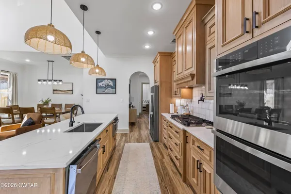a kitchen with stainless steel appliances a sink a stove and a wooden floors