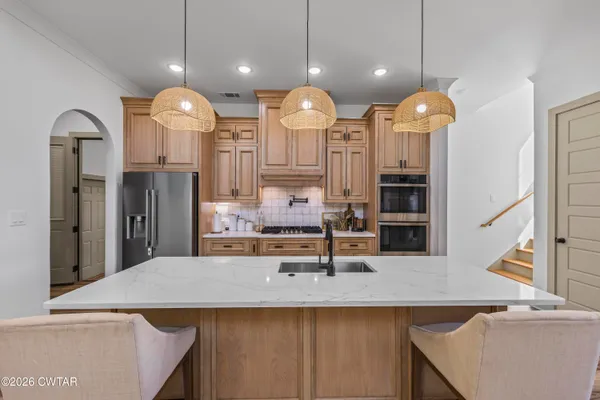 a view of a kitchen with a sink a center island and stainless steel appliances