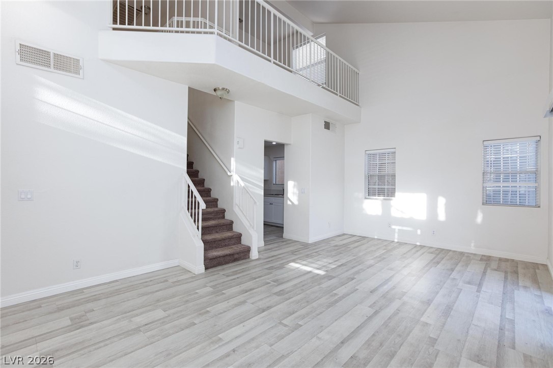 2246 Ramsgate Drive Henderson, NV 89074 - Photo 7 of 36 A spacious living area with soaring ceilings and light wood flooring, offering a seamless transition to the upper-level loft.