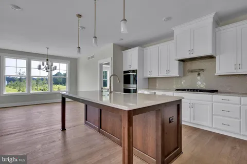 a kitchen with stainless steel appliances granite countertop a sink a stove and a wooden floor