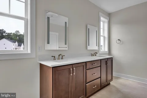 a bathroom with a two sinks a mirror and a window